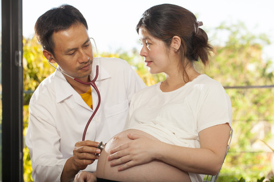 a male doctor using stethoscope check on pregnant woman