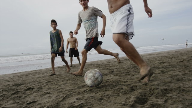Wide slow motion panning shot of people playing soccer on beach / Esterillos, Puntarenas, Costa Rica