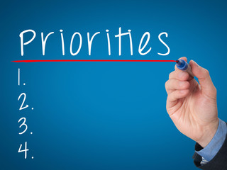 Business man hand writing Priorities list with marker