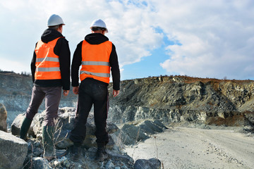 Two workers and quarry in background - obrazy, fototapety, plakaty