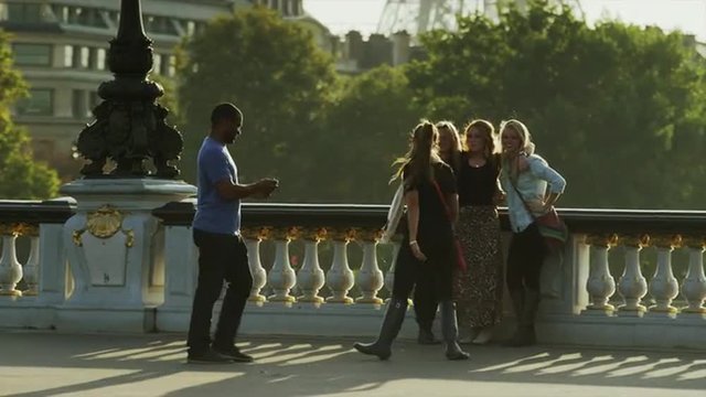 Medium shot of person taking photograph of tourists on bridge / Paris, France