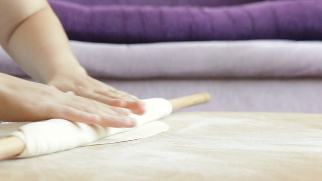 rolling out dough on the table with the help of a rolling pin