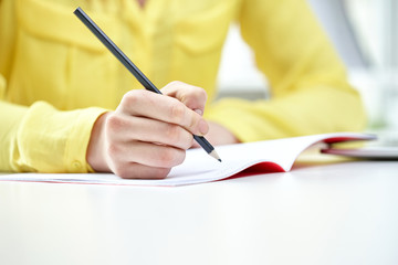 close up of female hands writing to notebook