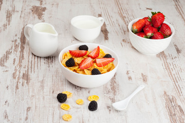 cornflakes with berries in a bowl and milk for breakfast, close-
