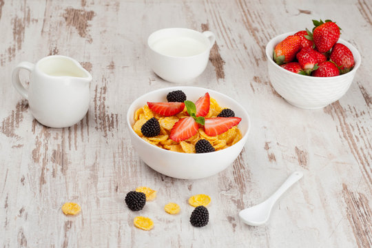 cornflakes with berries in a bowl and milk for breakfast