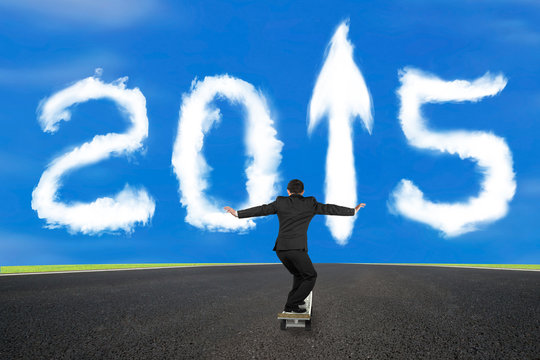 Businessman skateboarding on asphalt road with 2015 arrow up clo