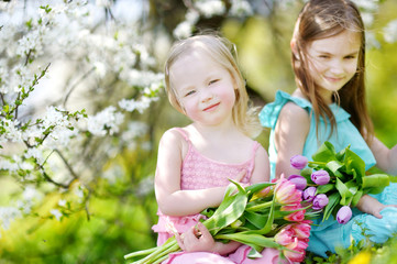 Two sisters holding flowers in a garden