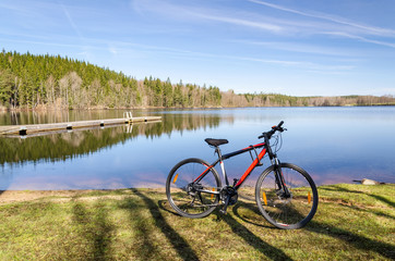 Fototapeta na wymiar Red bicycle on a lake coast