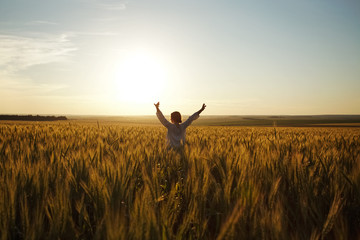 Woman stands in a field of ripe wheat