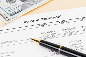 Income statement financial report with banknote and pen