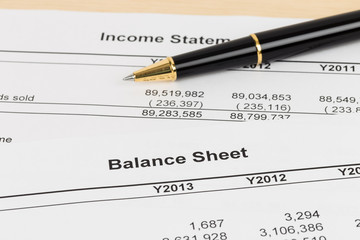 Balance sheet financial report with pen; document is mock-up