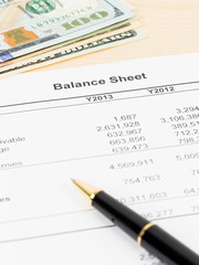 Balance sheet financial report with pen, and banknote