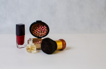 perfume in a transparent bottle, red nail polish and rouge on th