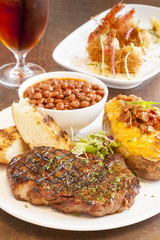 steak with baked potato, pinquito beans and grilled garlic bread
