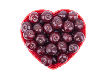 Cherries on a plate in the shape of a heart .
