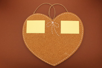 Two sticky notes on an isolated heart-shaped cork board