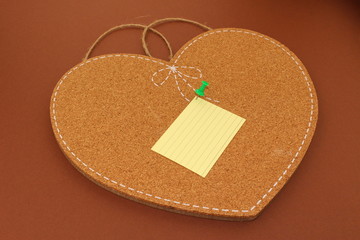 One sticky note on an isolated heart-shaped cork board