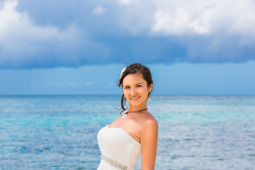 Fototapeta na wymiar beautiful fiancee in white wedding dress stand on shore sea. Wed