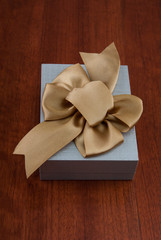 Holiday Gift Packed into Grey Box with Ribbon on Glossy Wooden T