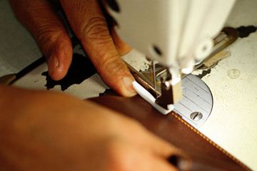 Old women's hands with sewing machine at textile factory