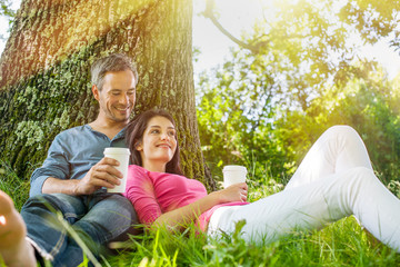 Fototapeta premium A nice couple sitting in the grass, having a coffee