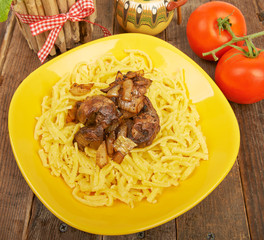 Noodles with fried liver and tomatoes on an old vintage table