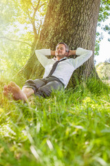 barefoot businessman taking a break,leaning against a tree