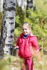 little girl collects birch sap in woods