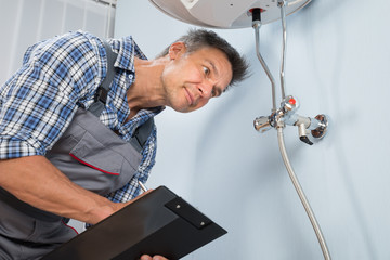 Obraz premium Plumber With Clipboard Looking At Electric Boiler