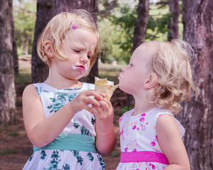 Pretty little girls (sisters) eating ice cream.