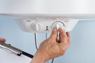 Person Adjusting Temperature Of Electric Boiler