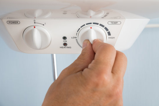 Person Adjusting Temperature Of Electric Boiler