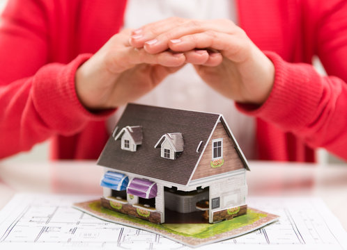 Closeup of female realtor hands showing house model to client.