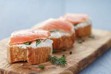 small sandwiches with soft cheese and salmon on wood table