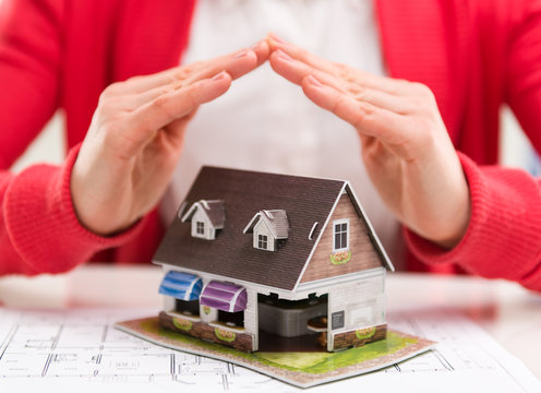 Close-up of mortgage agent with family house model in agency  