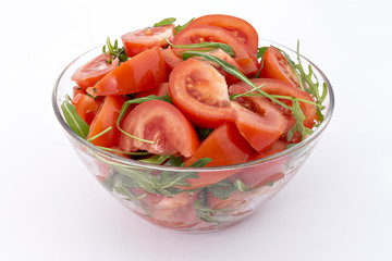 Tomatoes and rucola salad in glas bowl on white background