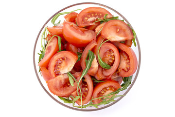Tomatoes and rucola salad in glas bowl on white background