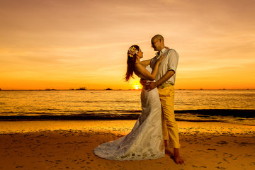 bride and groom having fun on a tropical beach with the sunset 