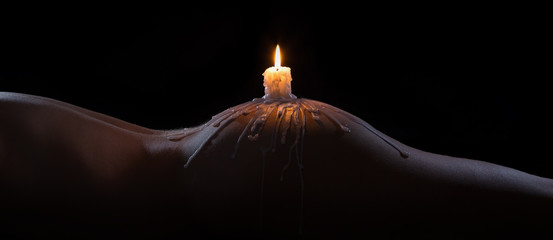 Body scape of a well-shaped woman with burning candle and wax on