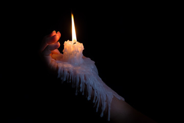 Open hand holding candle stick with wax flowing down the arm