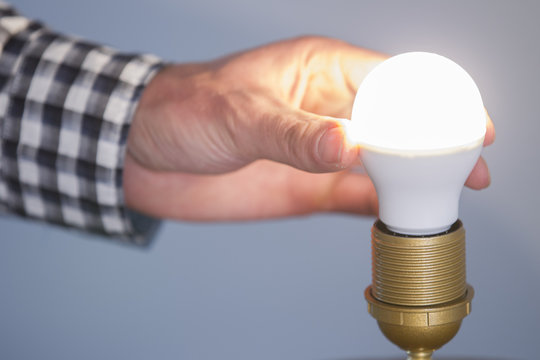 Hand Adjusting Lit Electric Bulb At Home