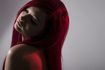 Beautiful red haired woman posing over grey background