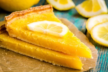 two pieces of lemon tart with slice of lemons closeup