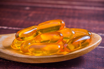 Fish oil on wooden spoon with wooden texture background