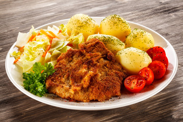 Fried pork chop, boiled potatoes and vegetable salad 