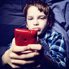 enfant garçon au lit avec smartphone