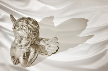 Figurine of a dreaming cherub on silk background