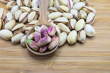 Pistachio nuts in wood spoon on wood background