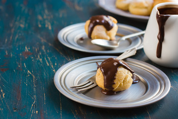 profiteroles with cream and chocolate sauce on dark blue backgro