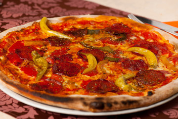 Hot pizza vith chili and salami served on a plate in italian res